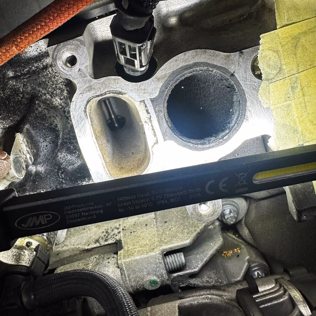 Ansaugkanäle eines Motors vor der Reinigung; dunkle Verkokungen sind am Einlasskanal sichtbar.